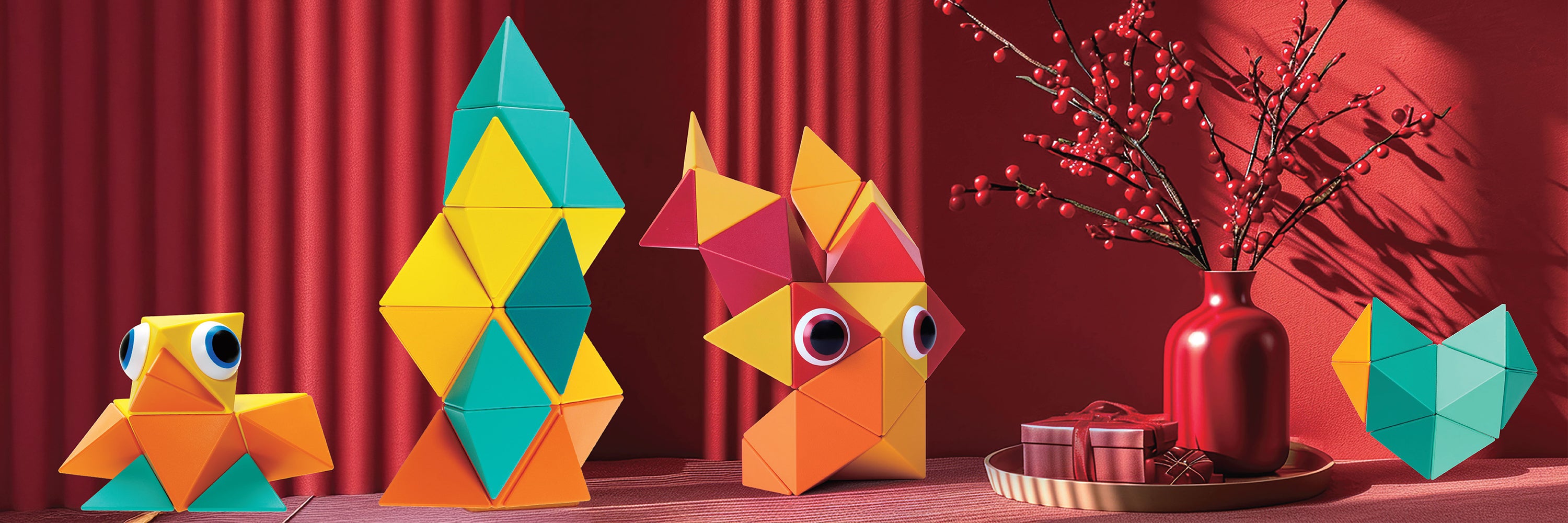 Colorful geometric animal toys on a wooden surface with a red curtain background