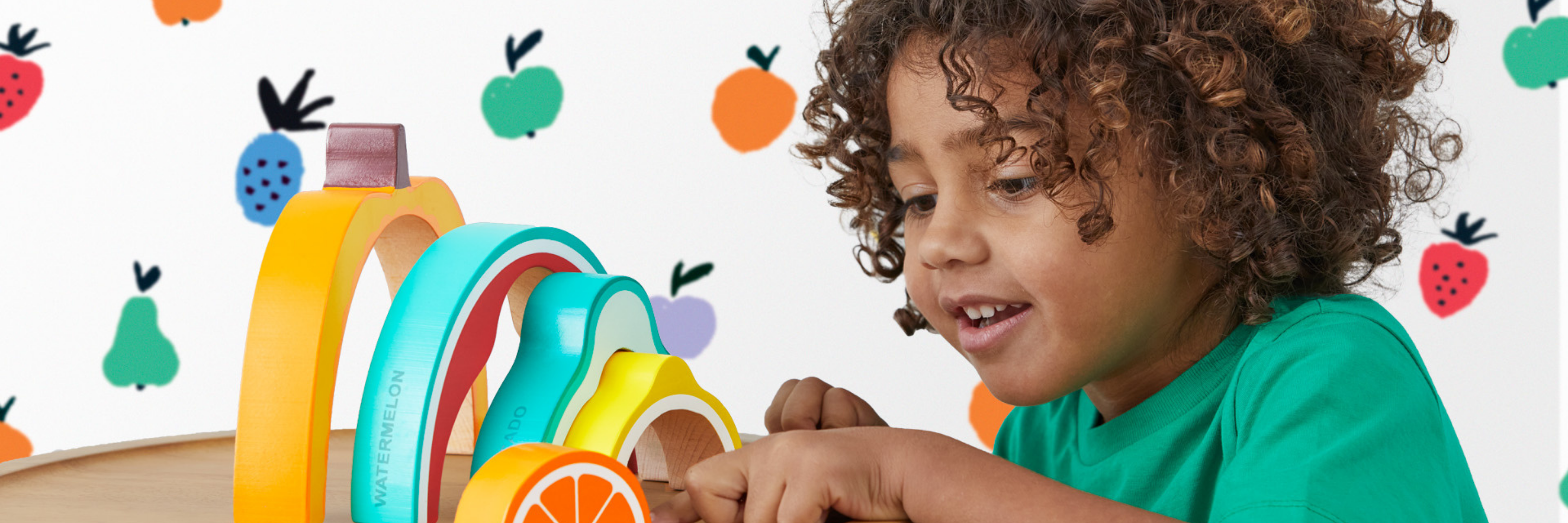 Child playing with colorful toy rings on a white background with fruit illustrations