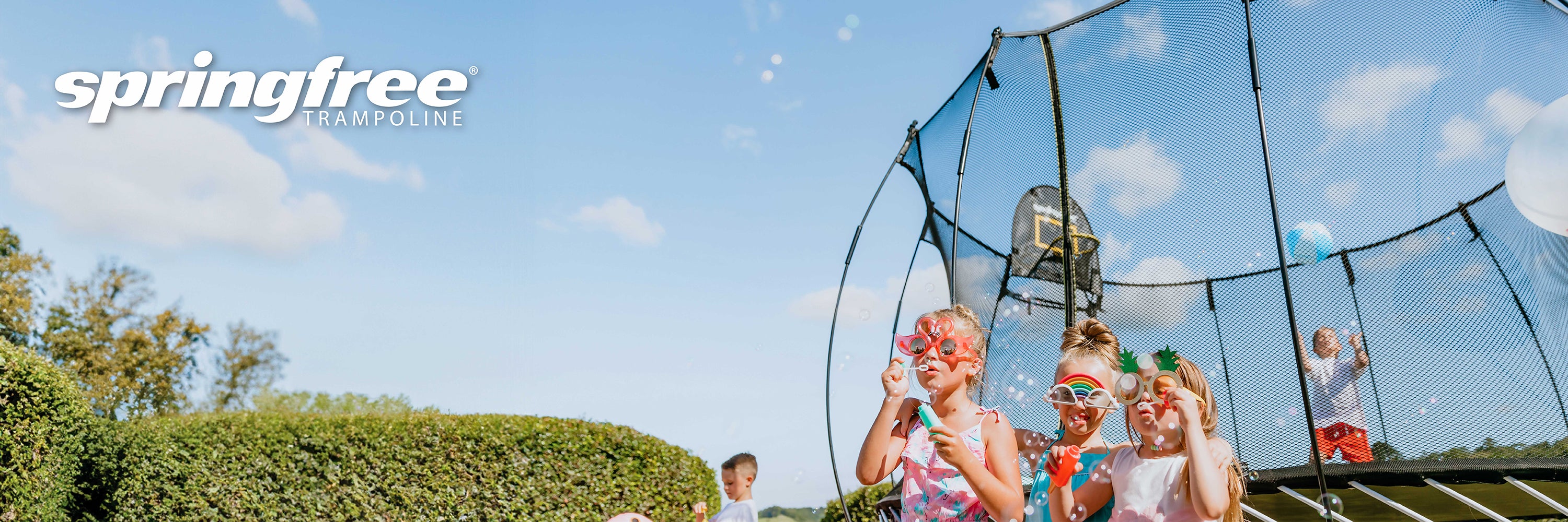 Children playing on a trampoline with 'springfree' branding against a blue sky.
