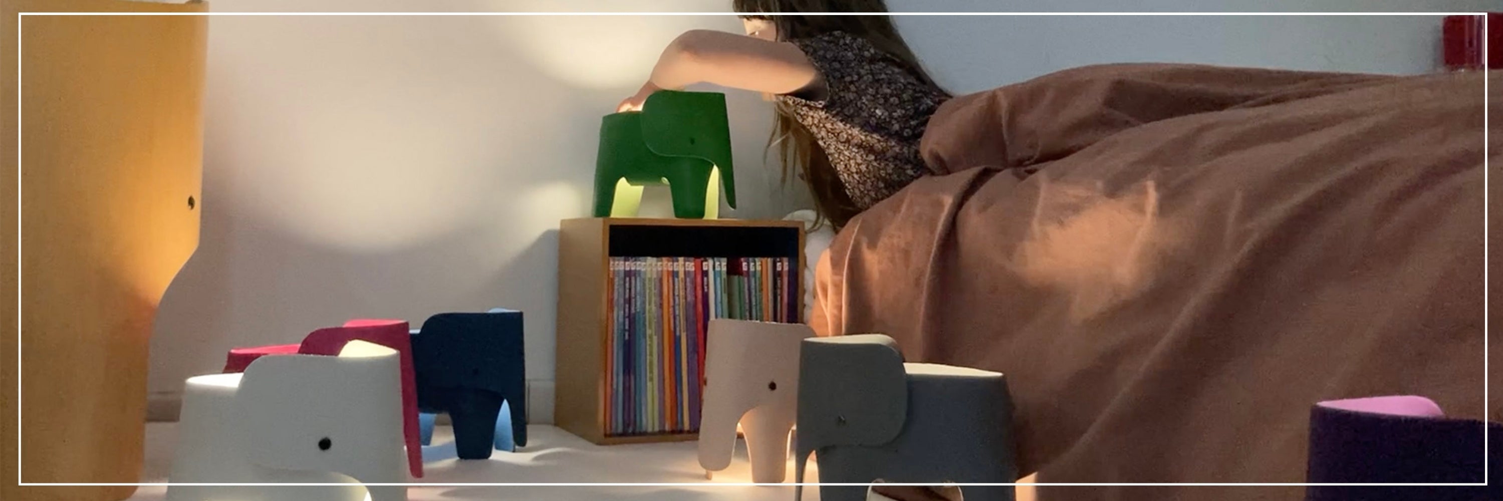 Person lying in bed with colorful nightstands and books in a bedroom setting