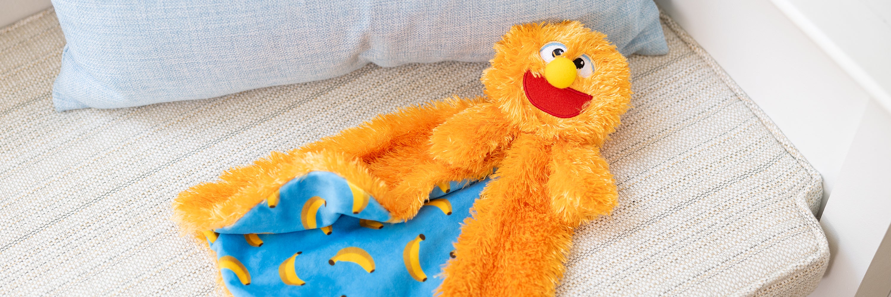 Orange plush toy with a blue blanket on a beige couch