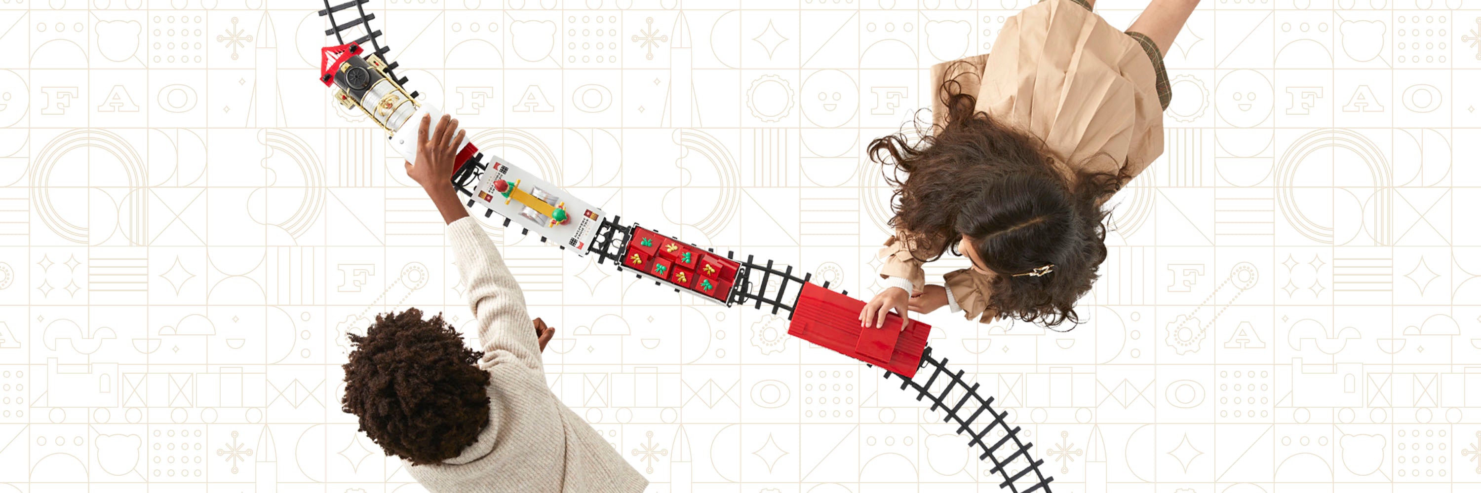 Two people holding hands over a toy train set on a white background