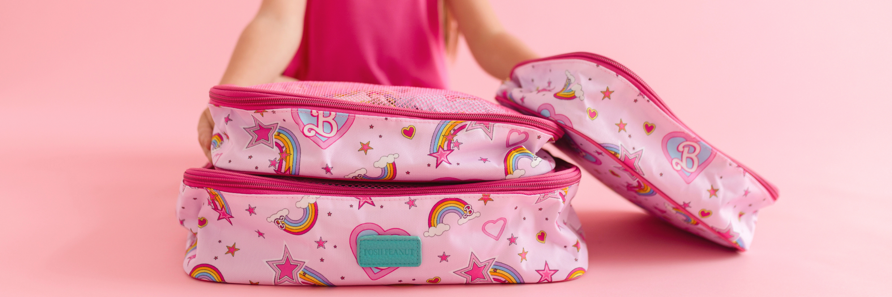 Pink travel bags with unicorn and rainbow patterns on a pink background