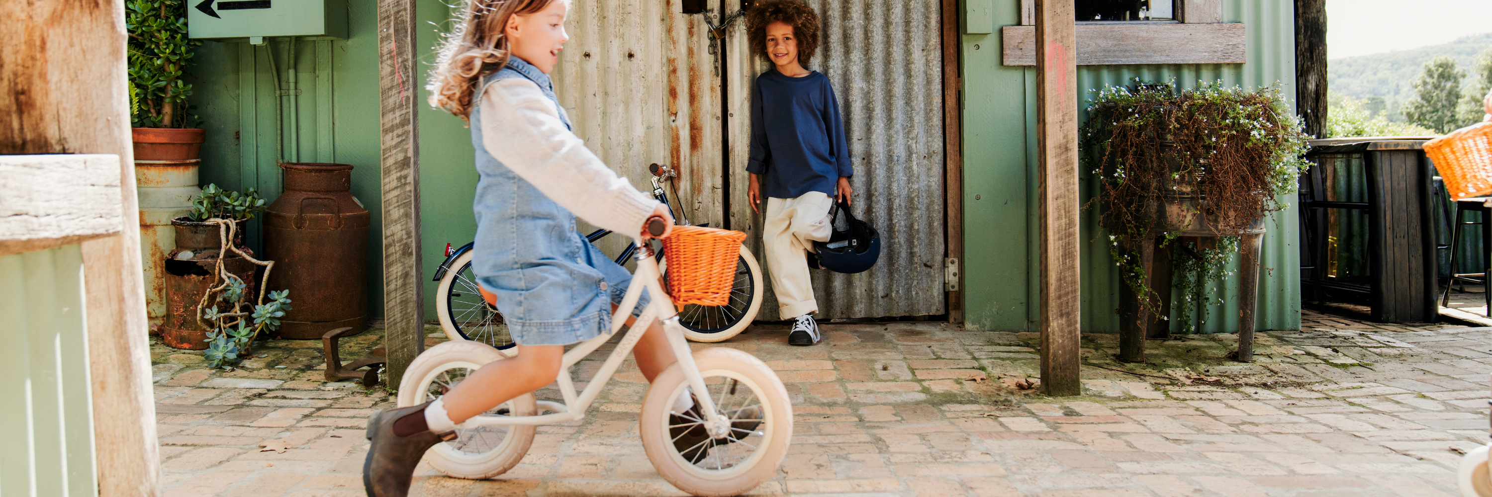 Two children with bicycles in a rustic outdoor setting.