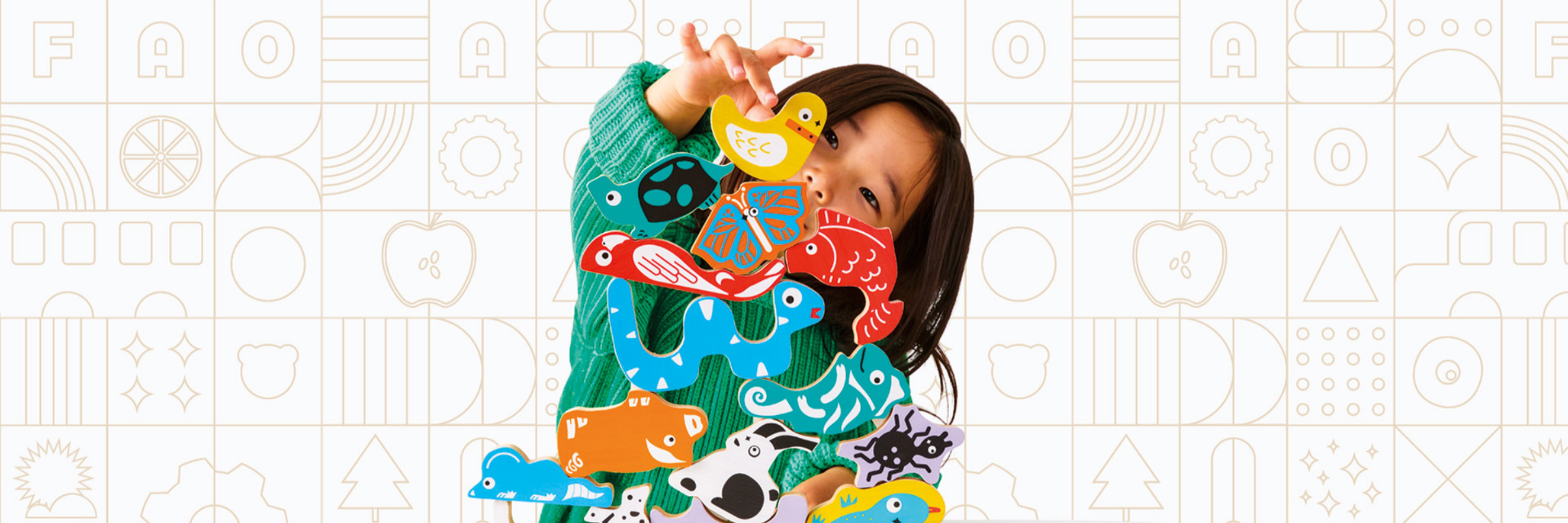 Child wearing a colorful sweater with cartoon character design on a patterned background