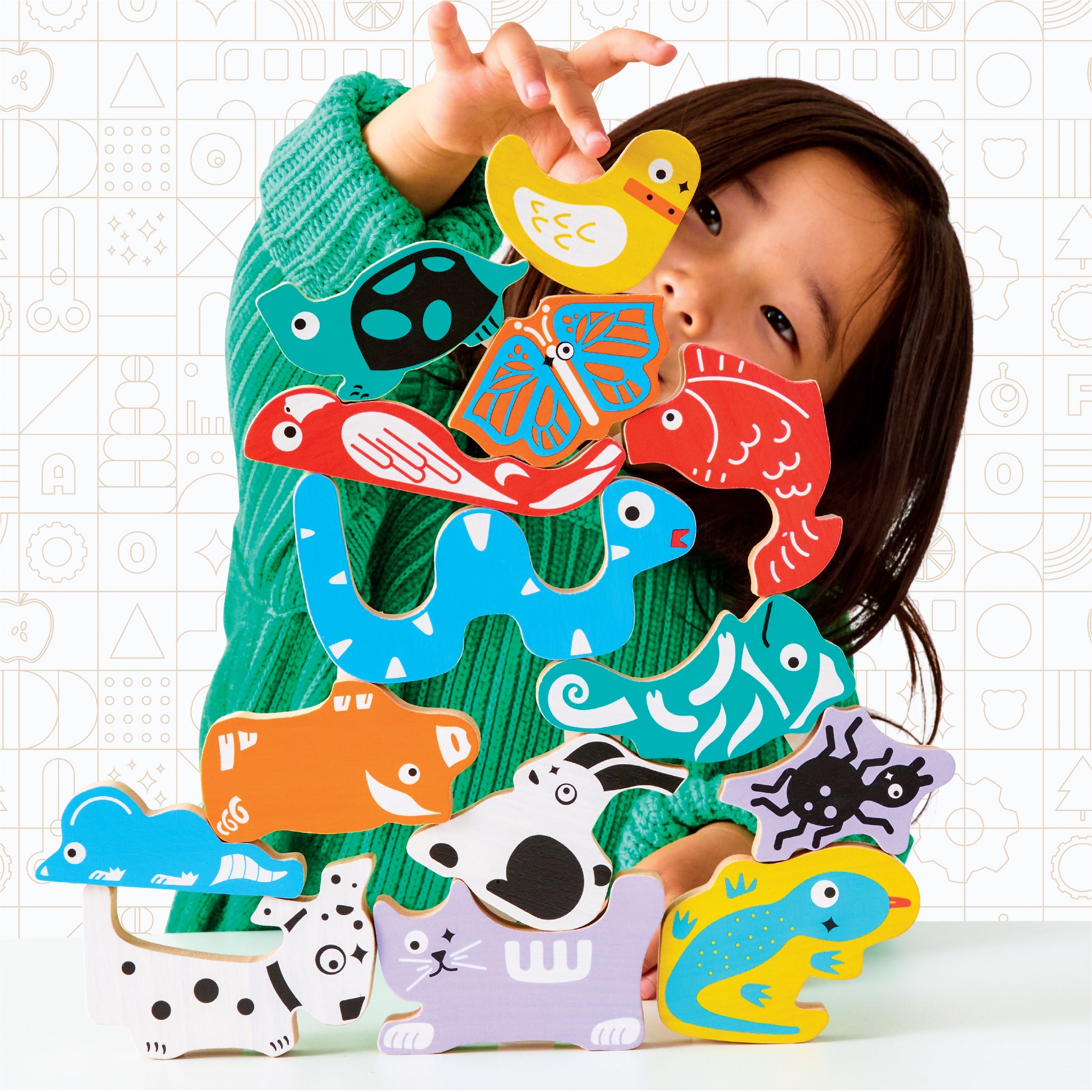 Child playing with colorful animal-shaped wooden toys on a white background