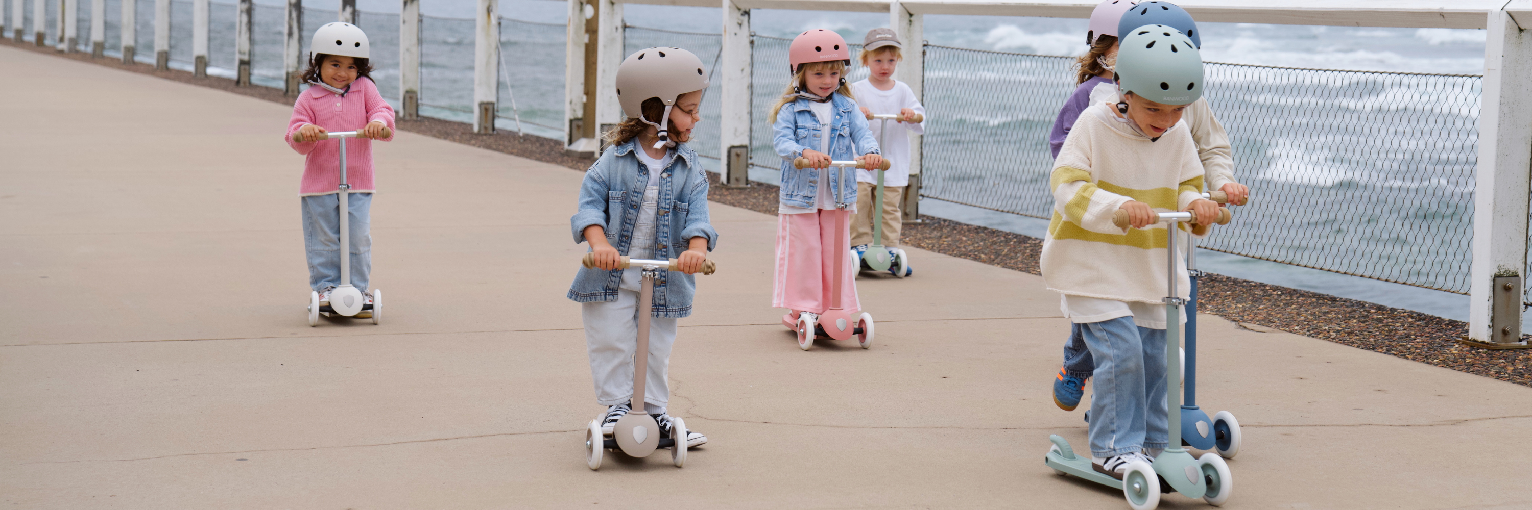 Children riding scooters on a boardwalk