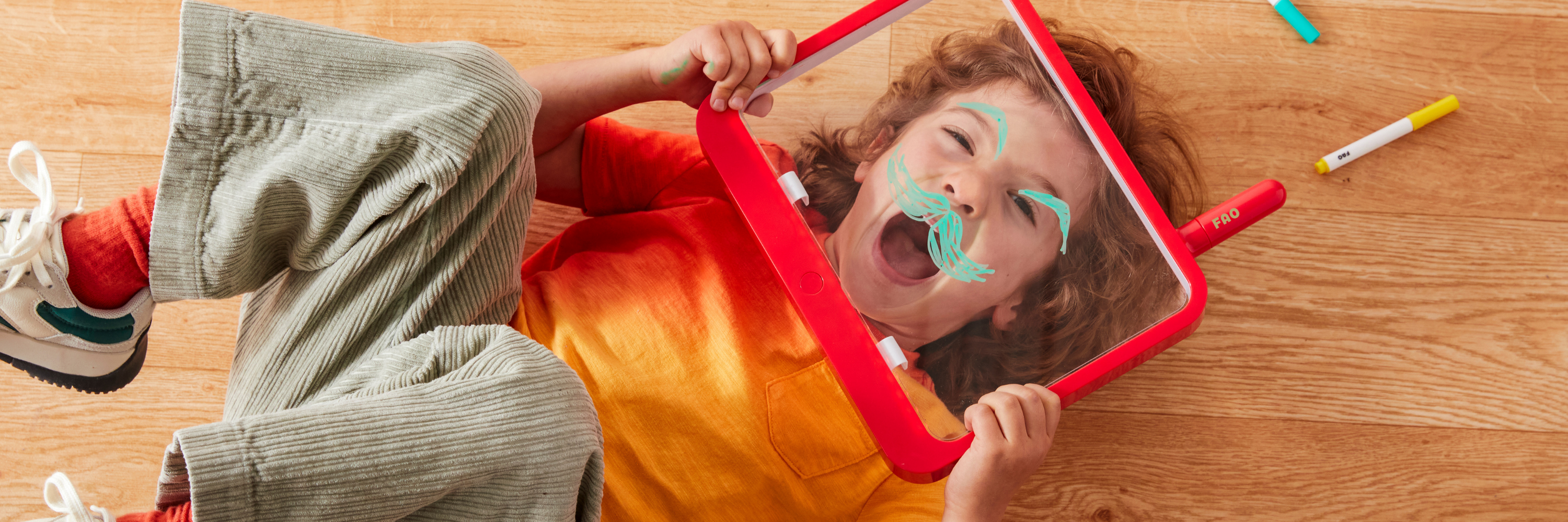 Child playing with a mirror on a wooden floor