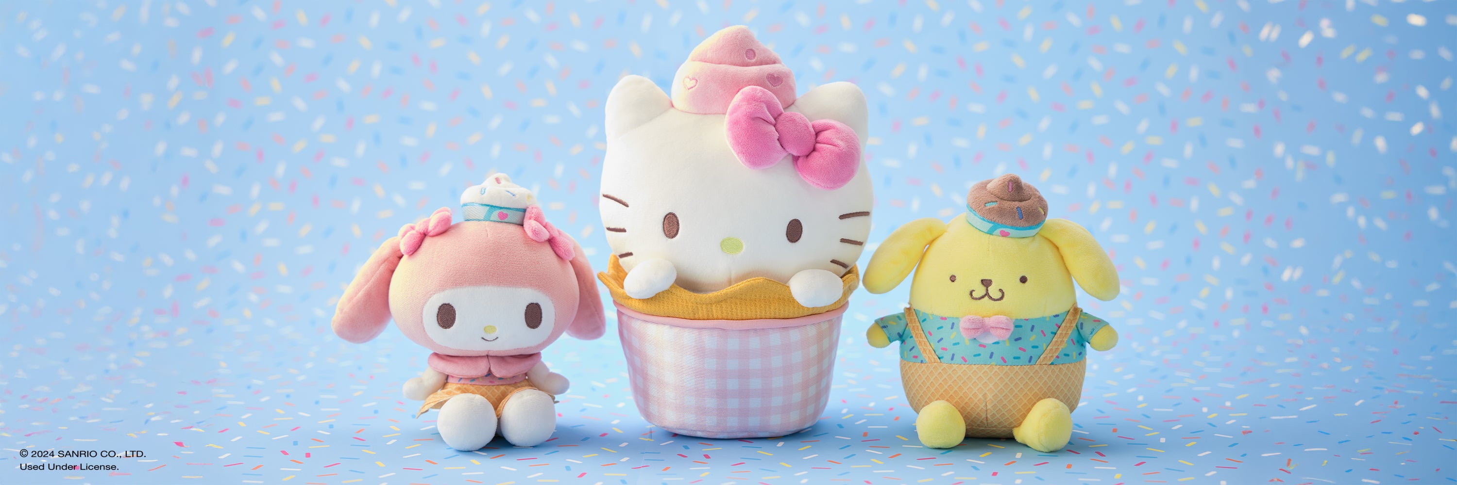 Three plush toys, including a cat-like character in a cupcake costume, on a blue background with snowflakes.