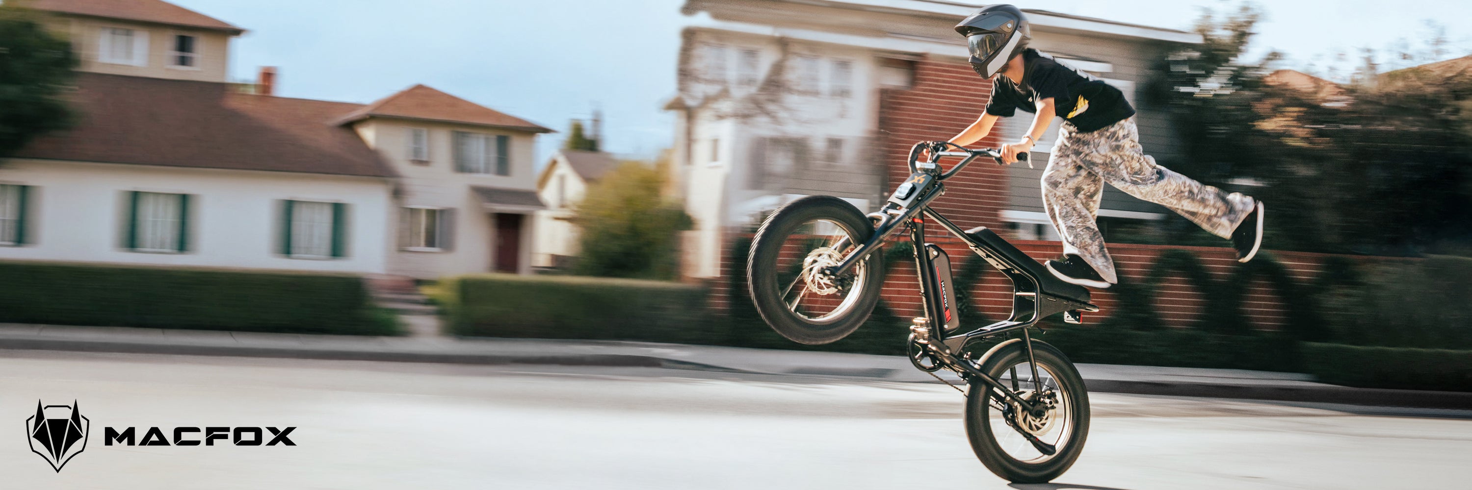 Child riding a balance bike on a residential street with 'Macfox' branding.