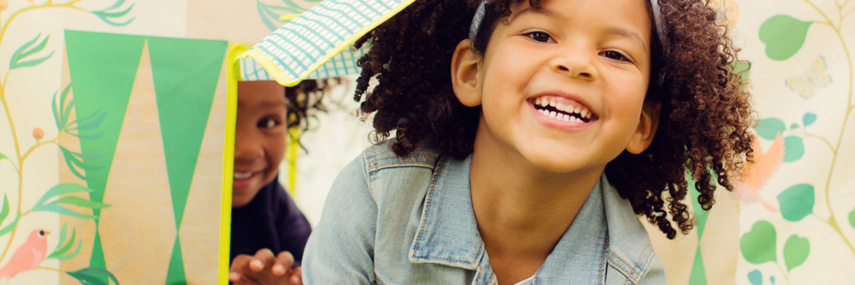 Child smiling with a colorful, nature-themed background