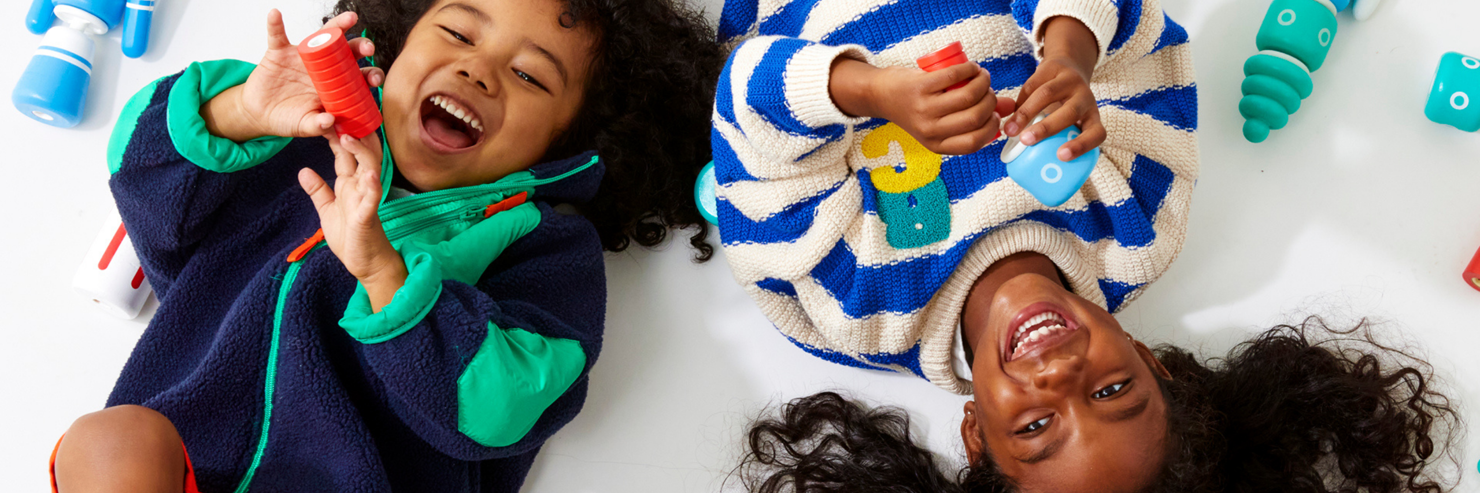 Two children playing with colorful toys on a white surface