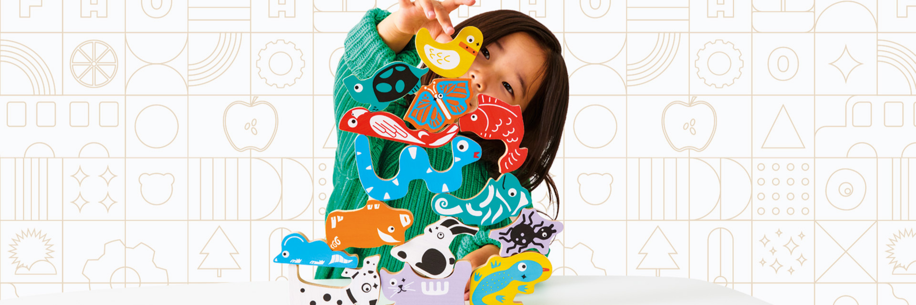 Child holding a colorful puzzle with animal shapes against a patterned background