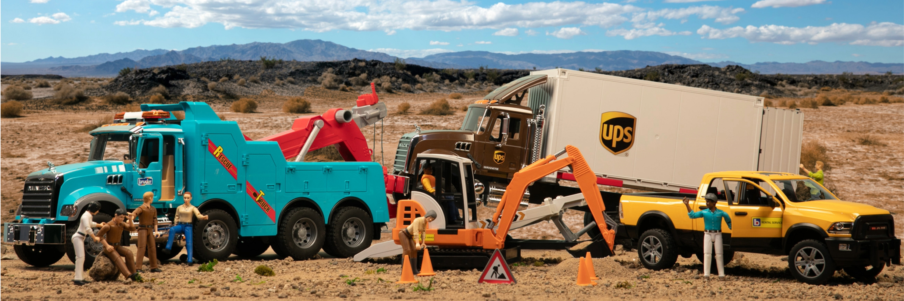 Toy construction vehicles and trucks in a desert setting with mountains in the background